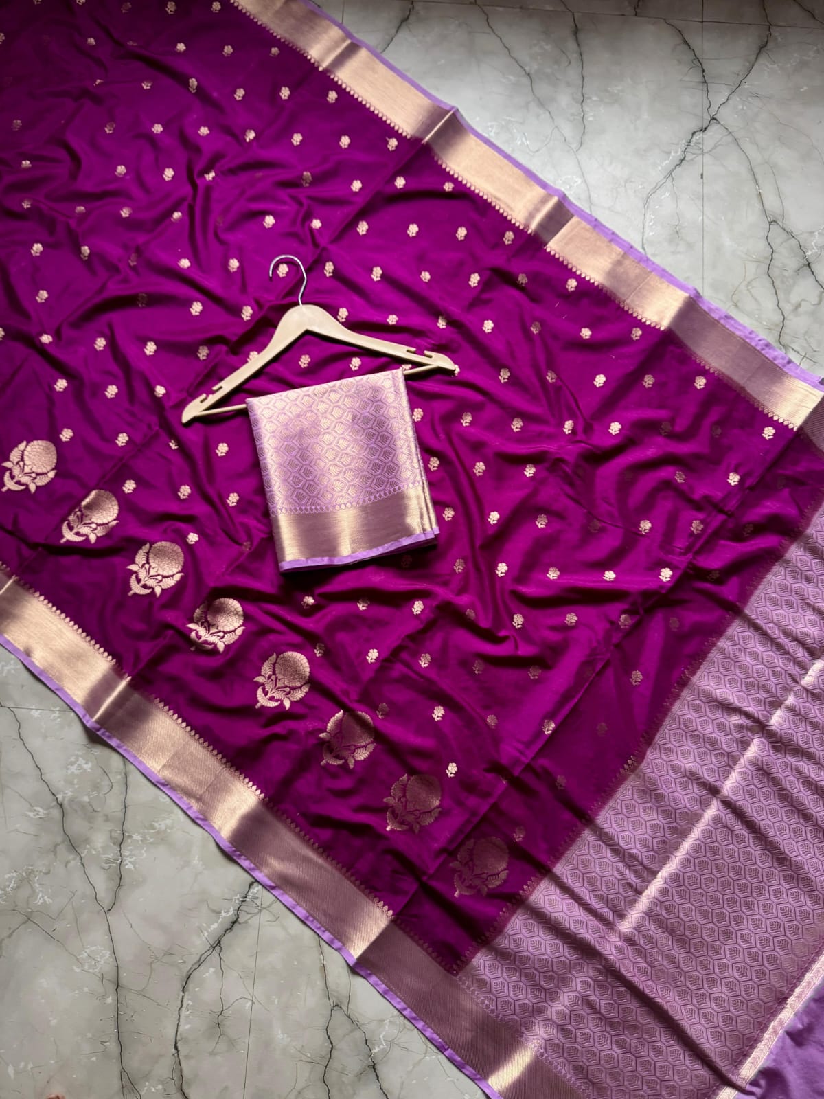 Purple saree with gold border and blouse on a textured surface