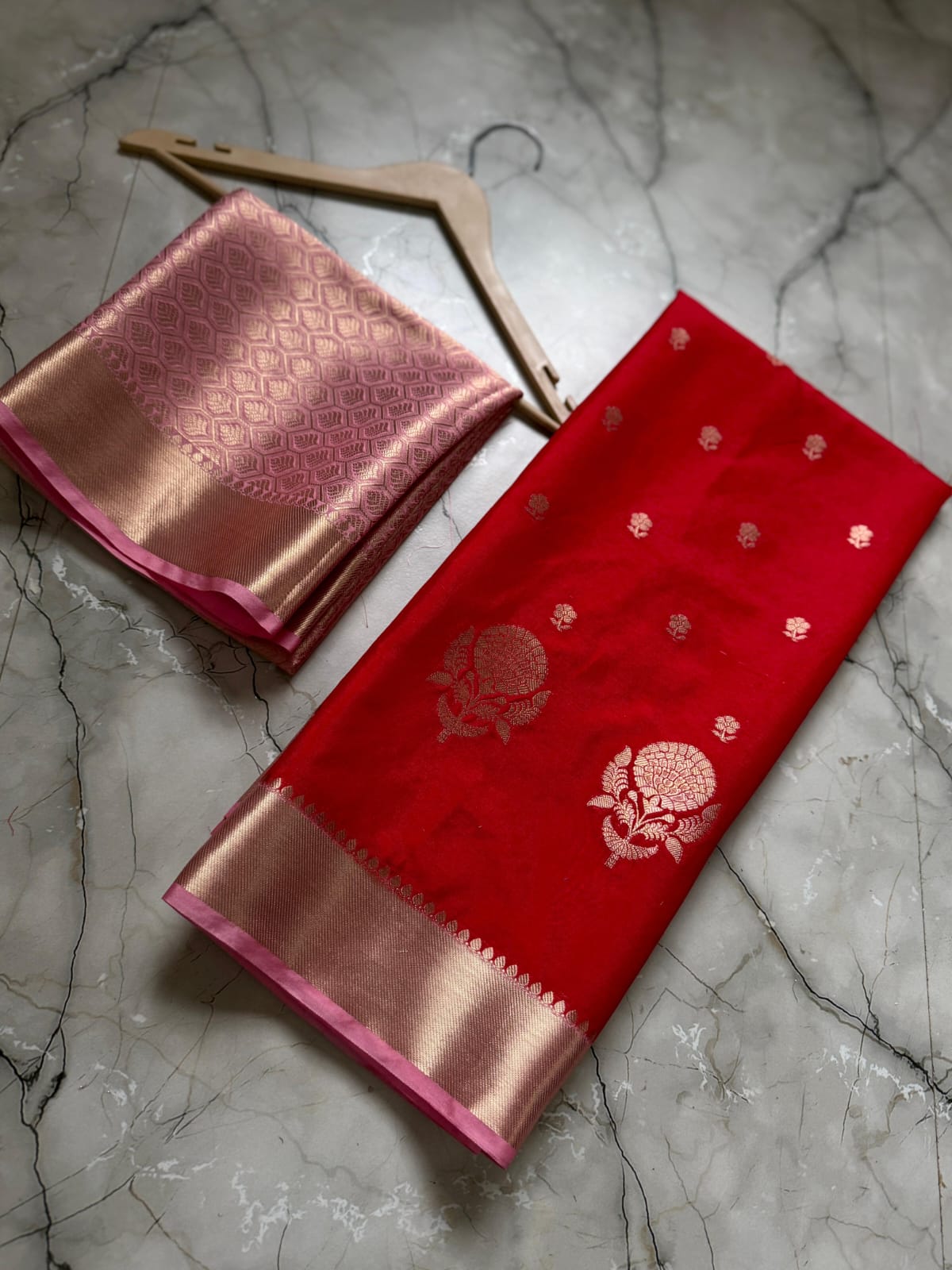 Red and pink saree with floral patterns on a marble surface