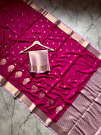 Pink saree with gold patterns on a hanger against a marble background