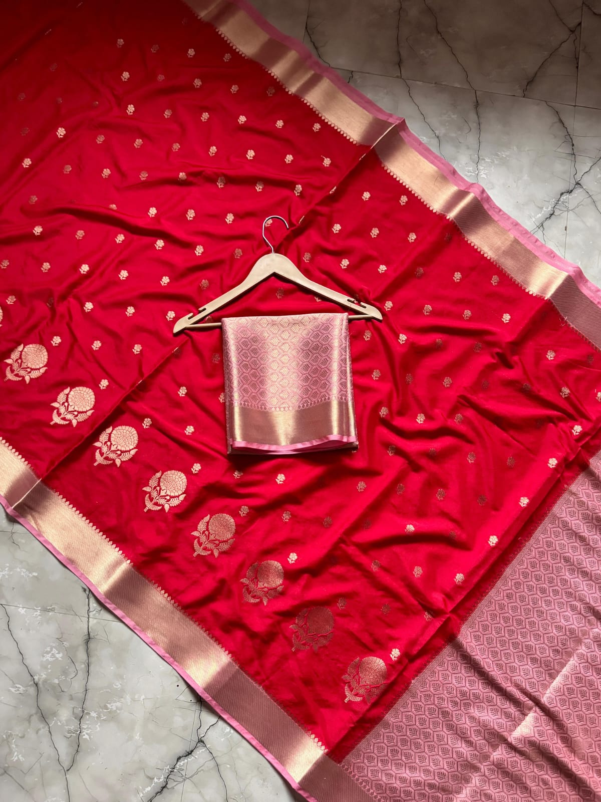 Red saree with gold border on a textured surface