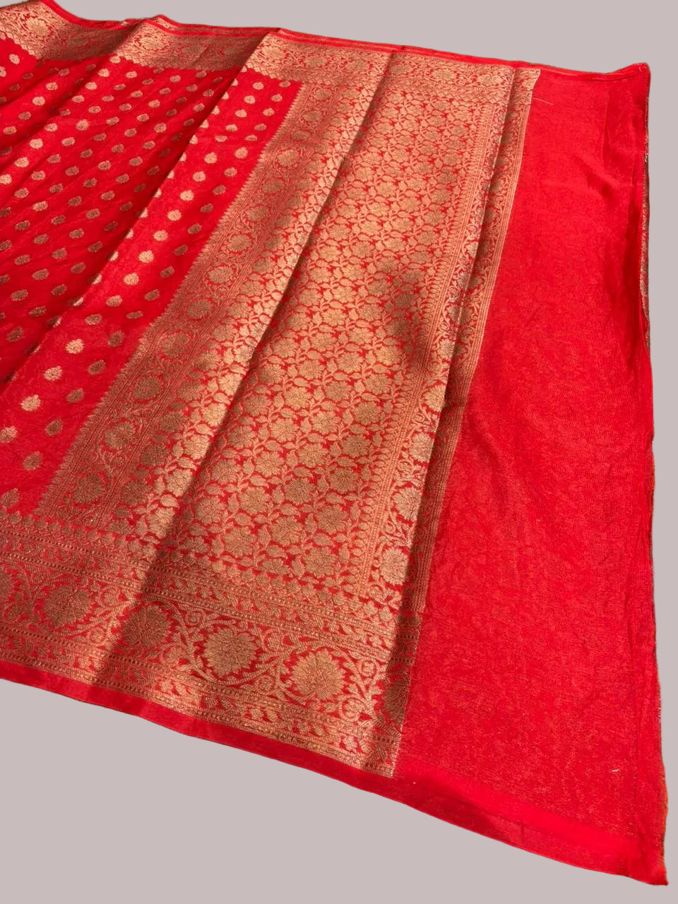 Red fabric with intricate patterns on a green grass background