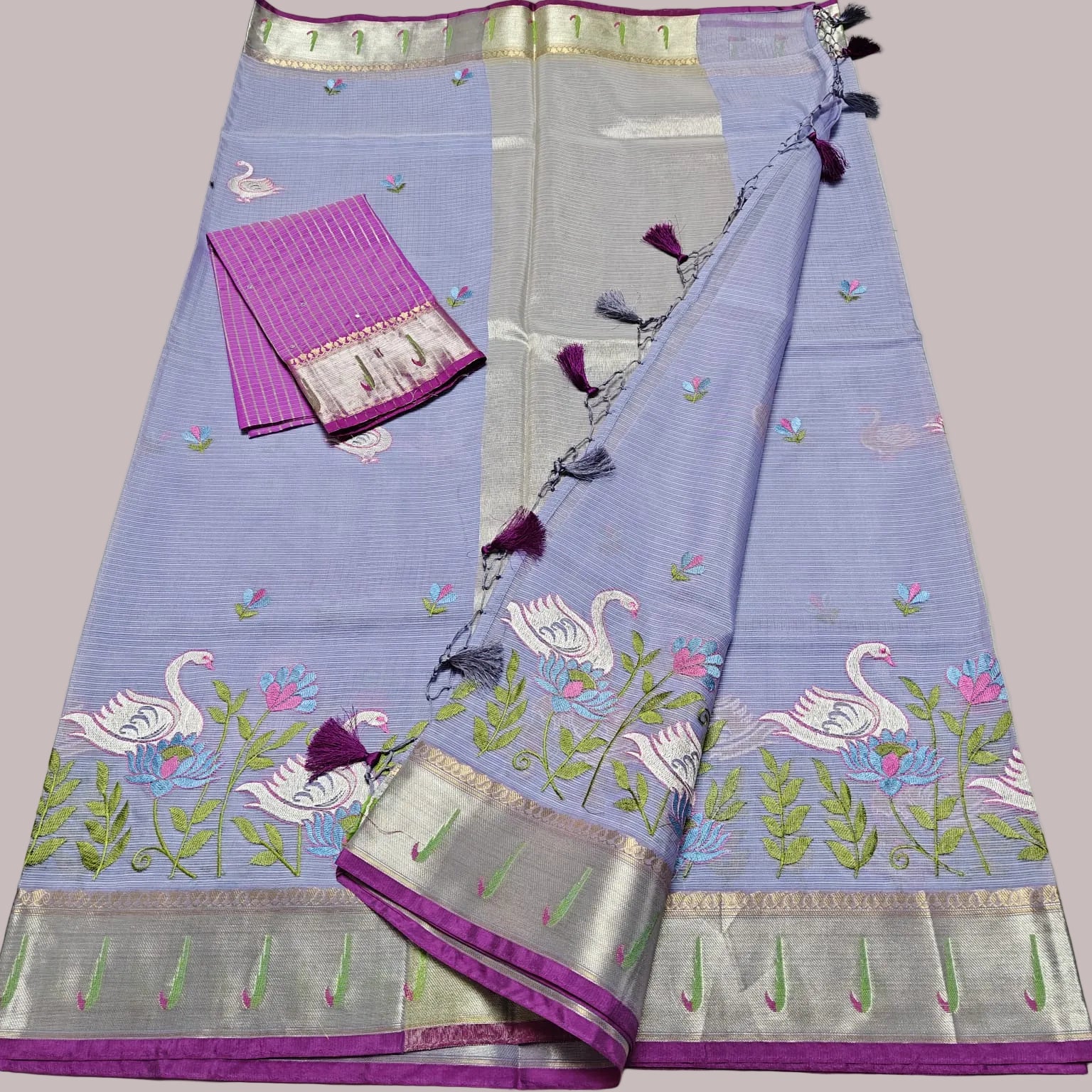 Purple saree with floral and bird patterns on a light gray background
