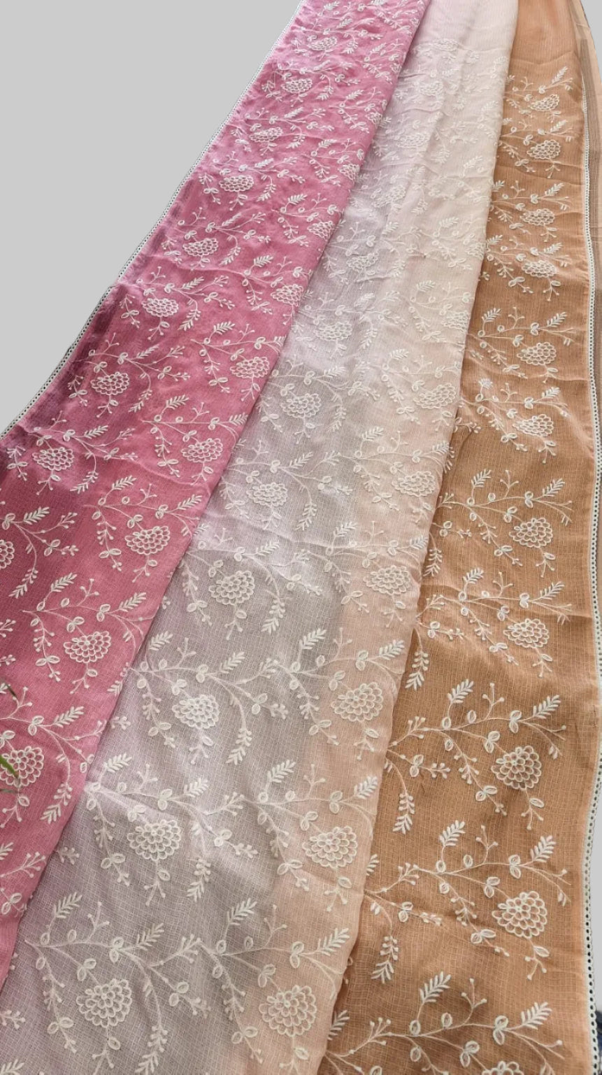 Three scarves in pink, beige, and brown with floral patterns draped over a surface with potted plants.