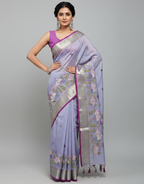 Woman wearing a light purple saree with floral patterns on a gray background