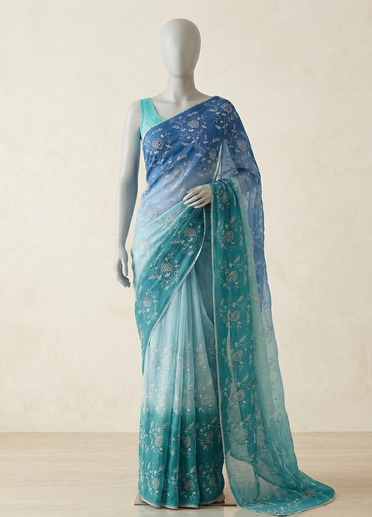 Mannequin wearing a blue and green saree with a subtle pattern on a light background