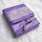 Folded purple fabric with intricate white patterns on a white background