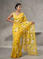 Woman wearing a yellow saree with floral patterns against a neutral background