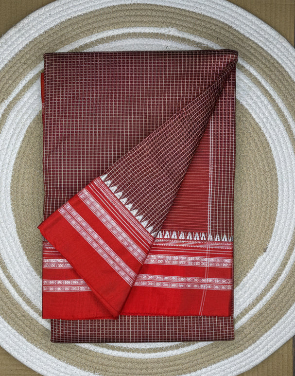 Two folded fabrics, one red with a checkered pattern and the other red with white patterns, on a circular woven mat.