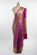 Pink saree with white floral patterns and gold border on a green and red checkered background