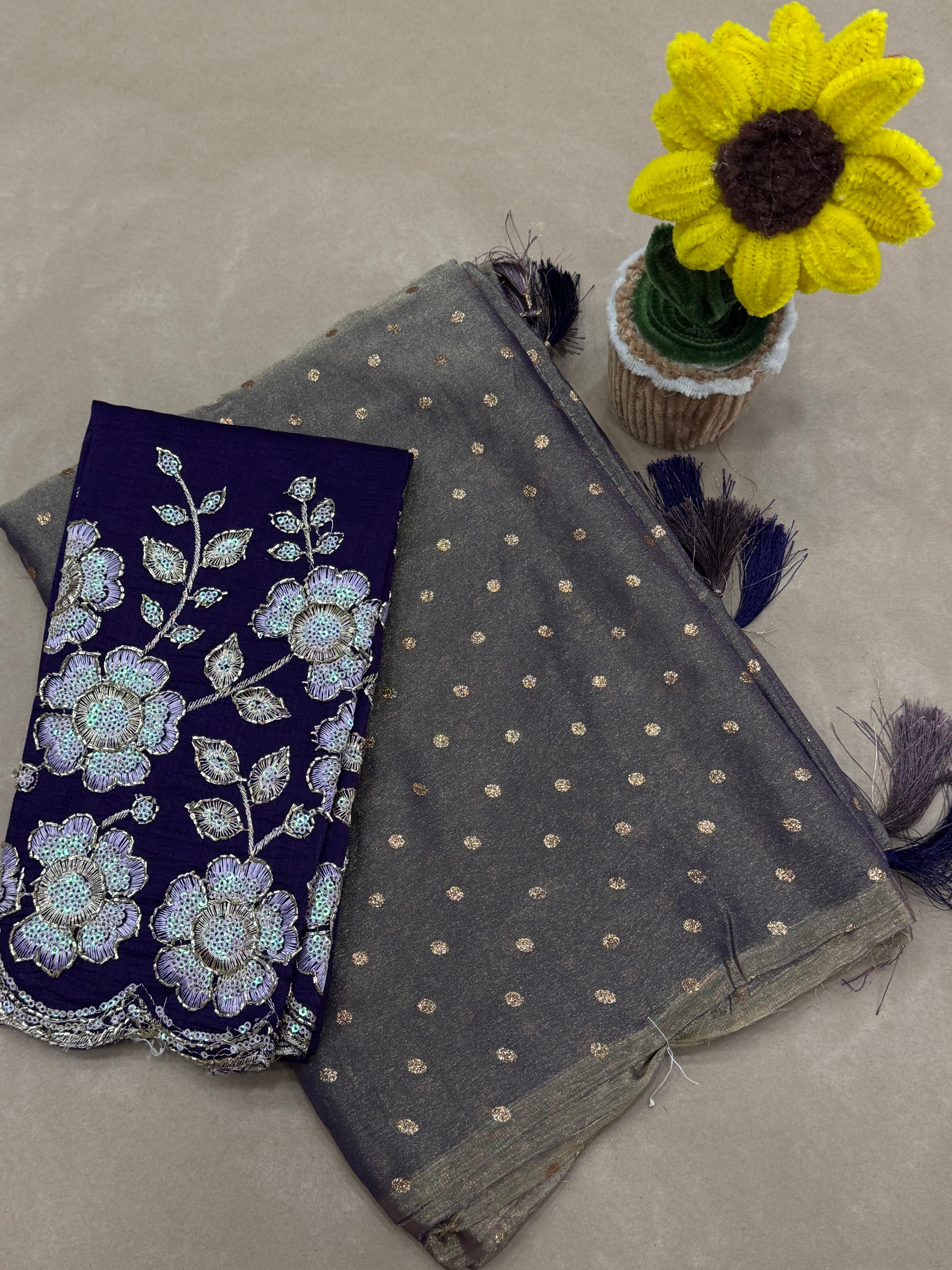 Gray fabric with white polka dots and a blue embroidered fabric with floral patterns on a beige surface.
