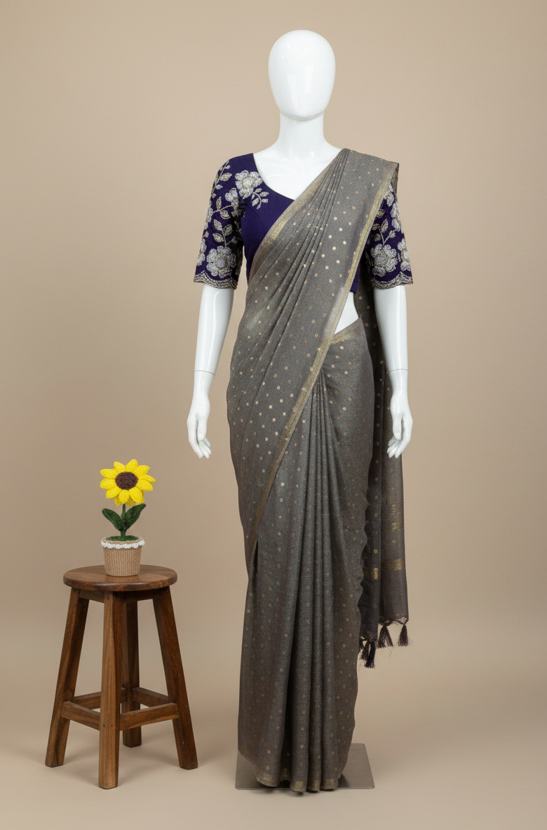 Gray saree with a white blouse on a mannequin, with a small wooden stool and sunflower decoration in the background.