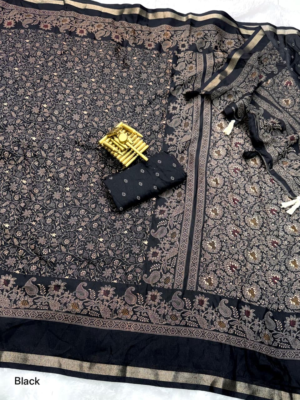Black floral patterned fabric with a small black pouch and gold item on top