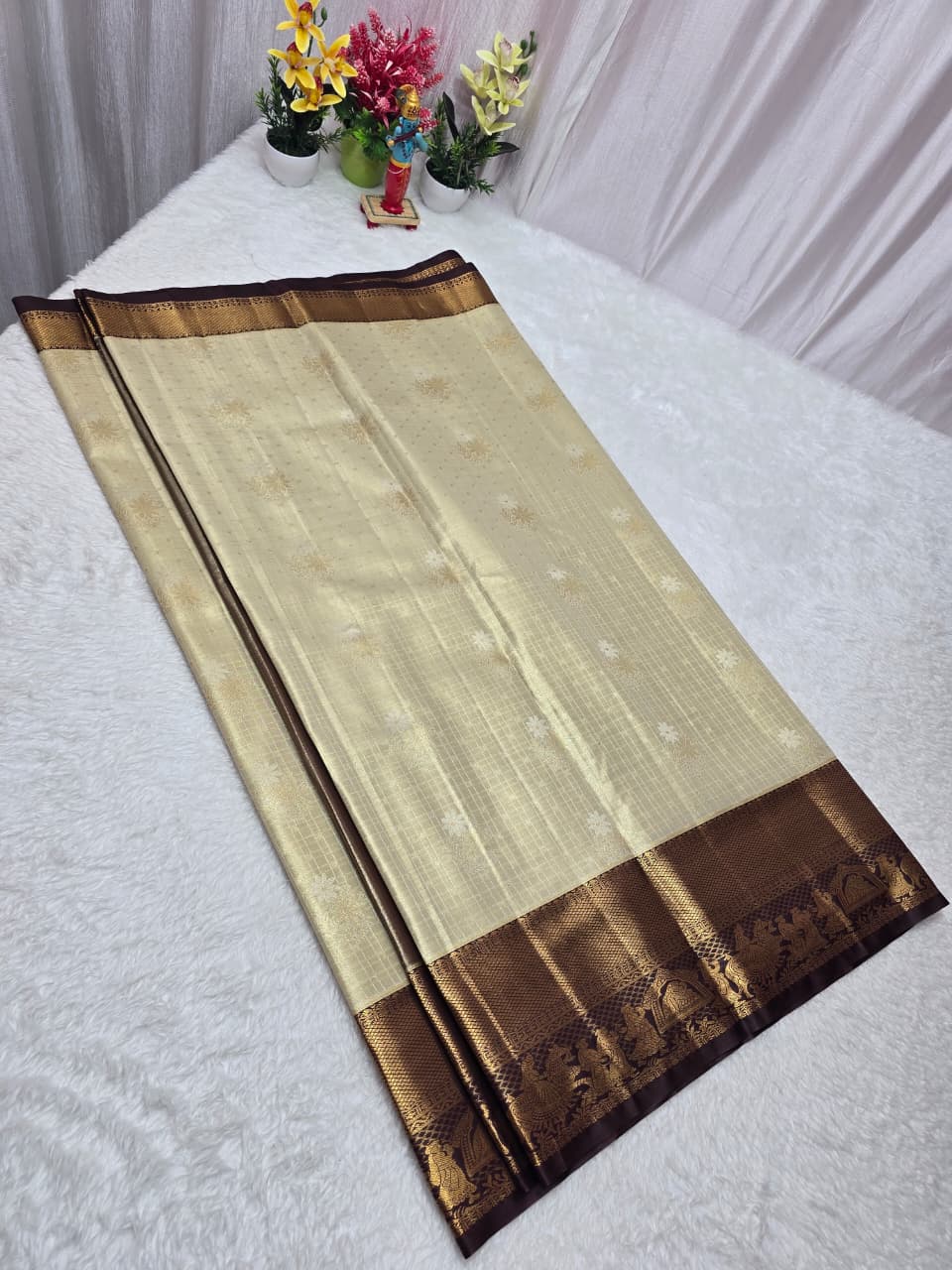 Beige and brown saree with floral decorations in the background