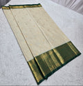 Traditional saree with green border on a white surface