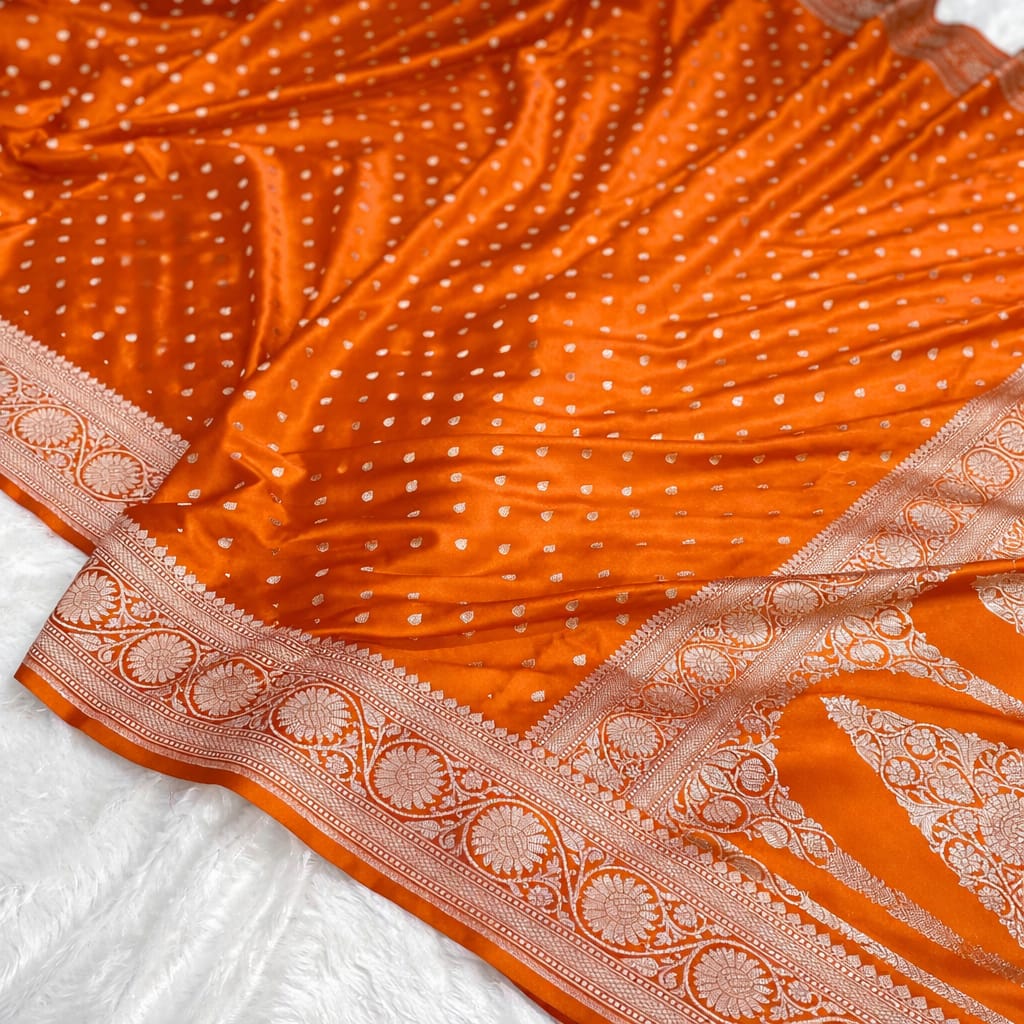Orange fabric with white polka dots and intricate border on a white background