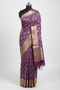 Purple saree with white floral patterns on a red and green checkered floor.
