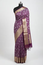 Purple saree with white floral patterns on a red and green checkered floor.