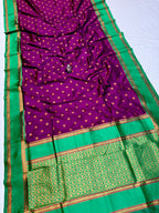 Purple saree with gold polka dots and green border on a white background
