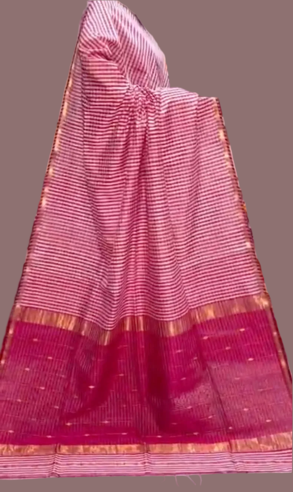 Pink saree with a gold border on a tiled floor