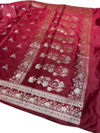Red saree with gold and white floral patterns on a wooden surface