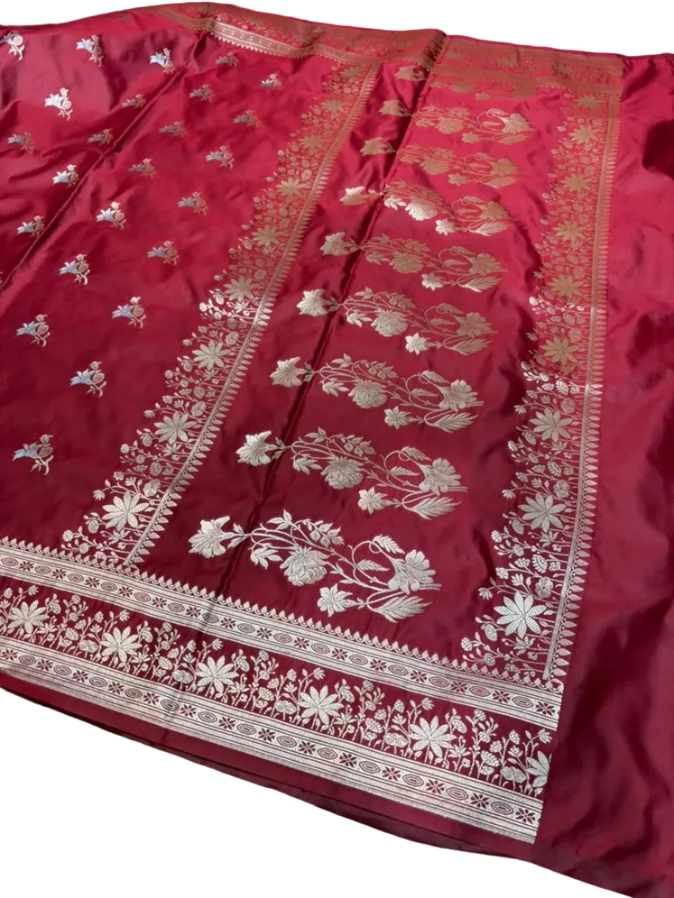 Red saree with gold and white floral patterns on a wooden surface