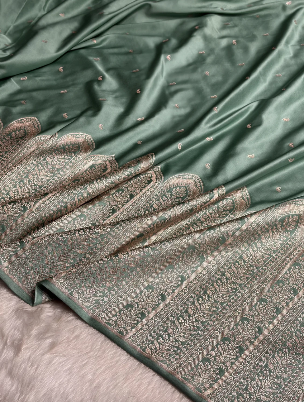 Green fabric with intricate patterns and a pair of gloves on top