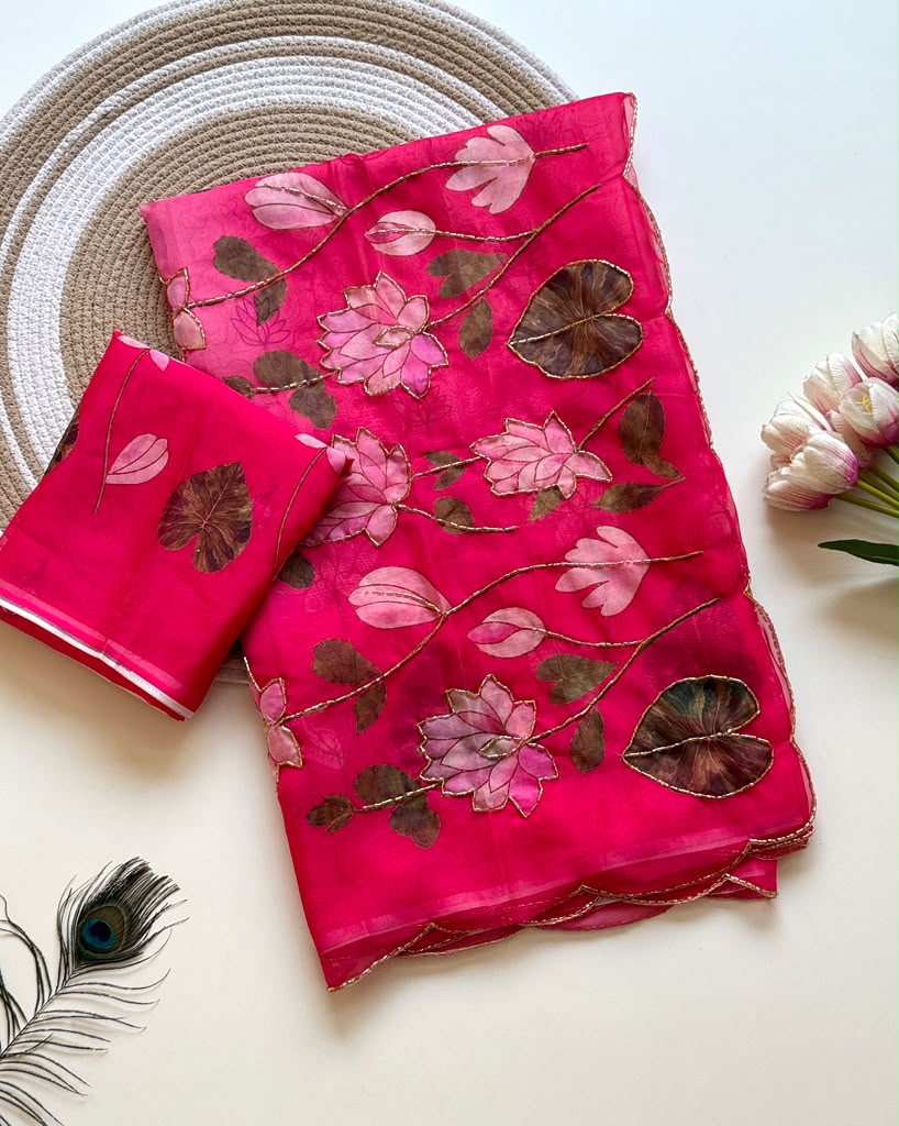 Pink Tebby silk saree with pink lotus digital floral prints, green leaf motifs, gold-tone Katdana detailing, scalloped edges and a matching running blouse.