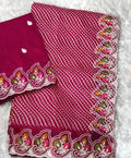 Pink fabric with white patterns and colorful embroidery held by a hand on a white background