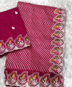 Pink fabric with white patterns and colorful embroidery held by a hand on a white background
