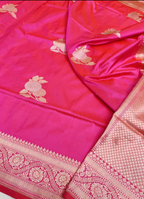 A close-up of a pink Banarasi silk saree with gold floral motifs and a detailed gold zari border.