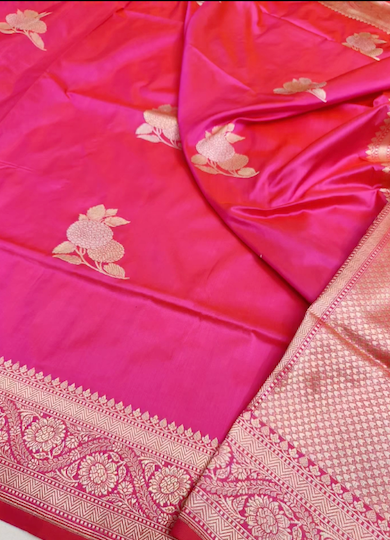 A close-up of a pink Banarasi silk saree with gold floral motifs and a detailed gold zari border.