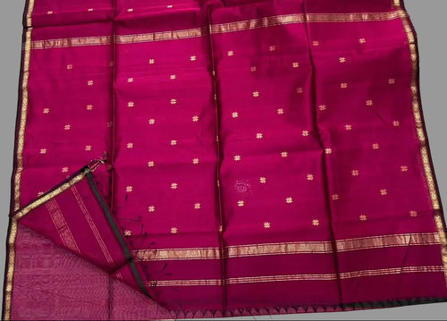 Pink saree with gold border on a white floor