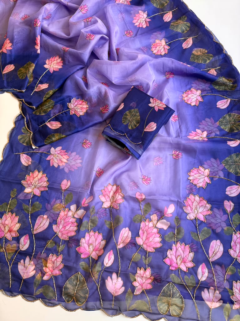 Purple Tebby silk saree with pink lotus digital floral prints, green leaf motifs, gold-tone Katdana detailing, scalloped edges and a matching running blouse.