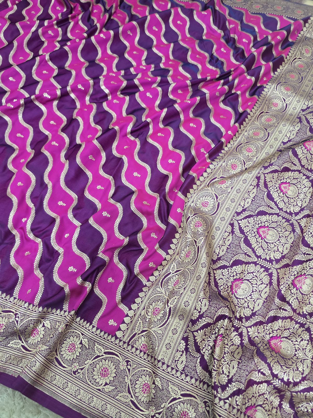 A close-up of a purple and magenta Banarasi silk saree with intricate silver zari woven patterns and borders.