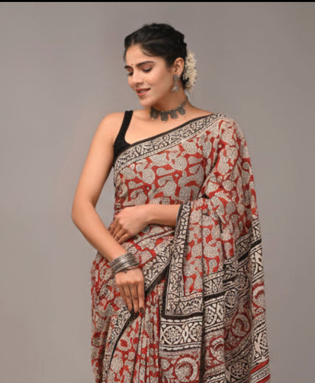Woman wearing a patterned saree against a plain background