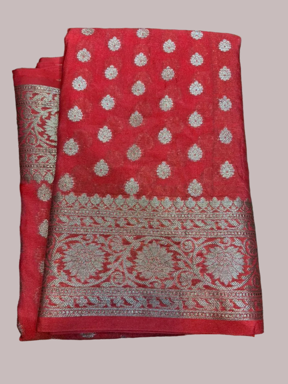 Red saree with white patterns on a green grass background