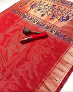 Red saree with floral patterns and a decorative item on a wooden surface