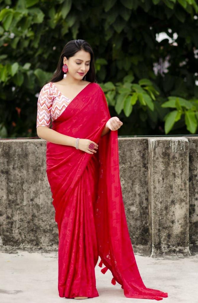 Woman in a red saree with a white blouse against a green foliage background