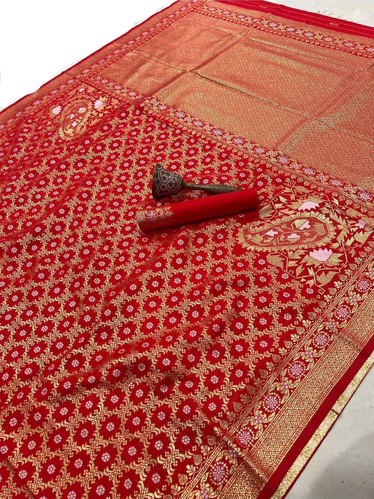 Red and gold patterned fabric with a decorative brooch on a white background