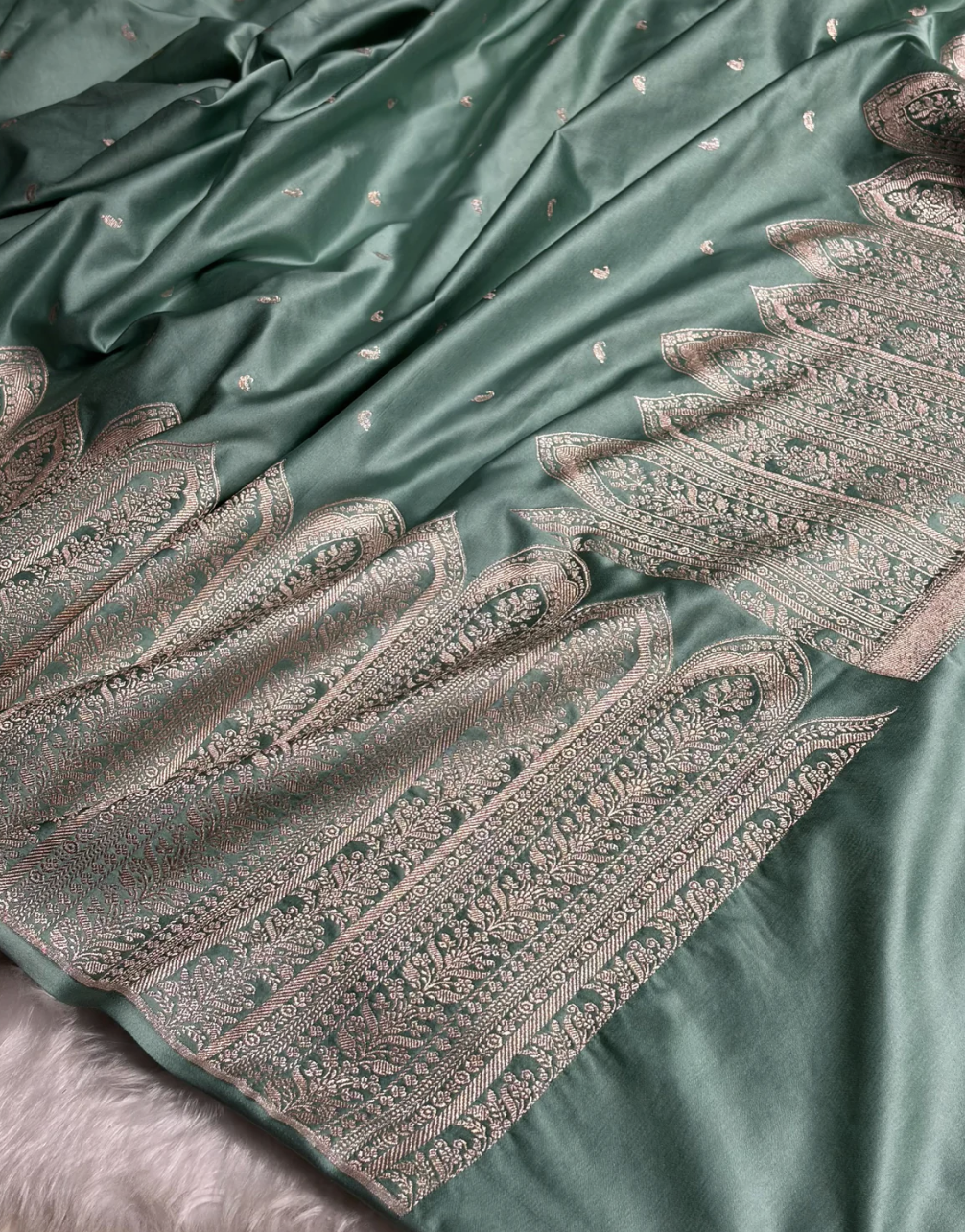 Teal fabric with intricate silver embroidery on a matching background