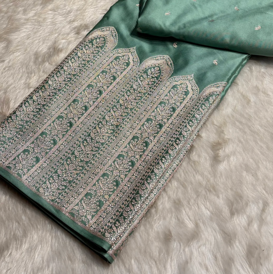 Green fabric with intricate white patterns on a textured surface