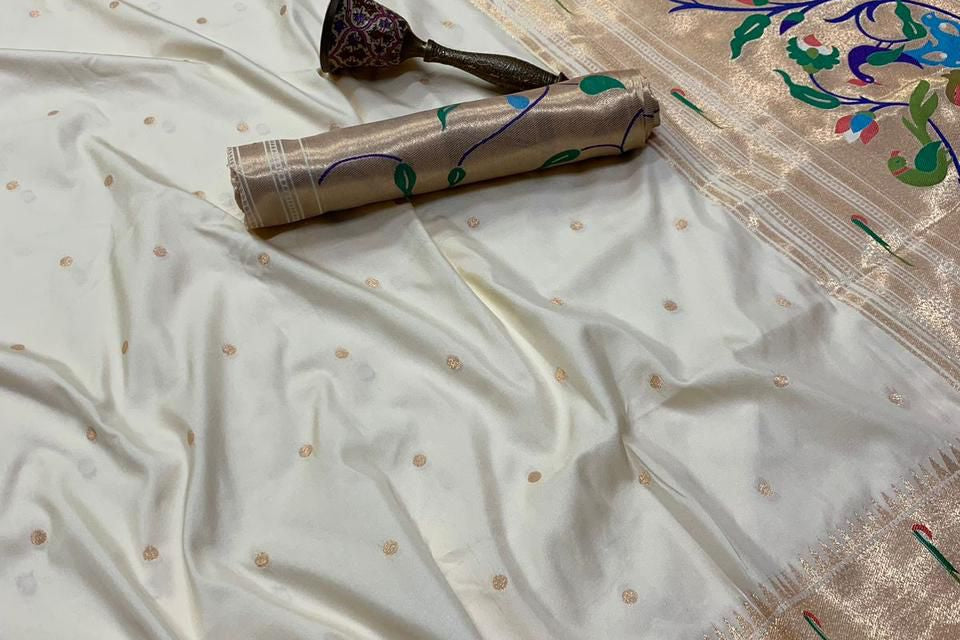 White saree with gold border and floral patterns on a plain background