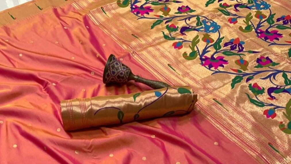 Decorative pink and gold fabric with floral patterns on a table.