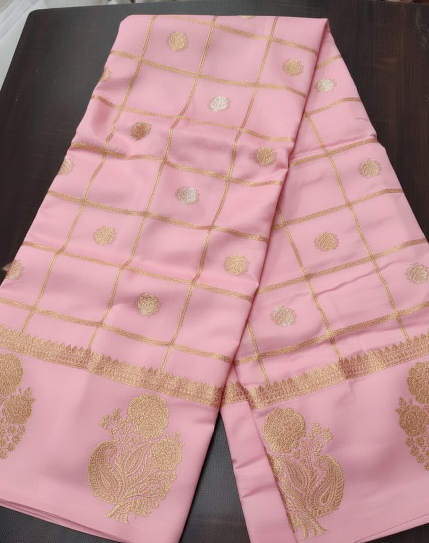 Pink fabric with gold embroidery on a dark surface