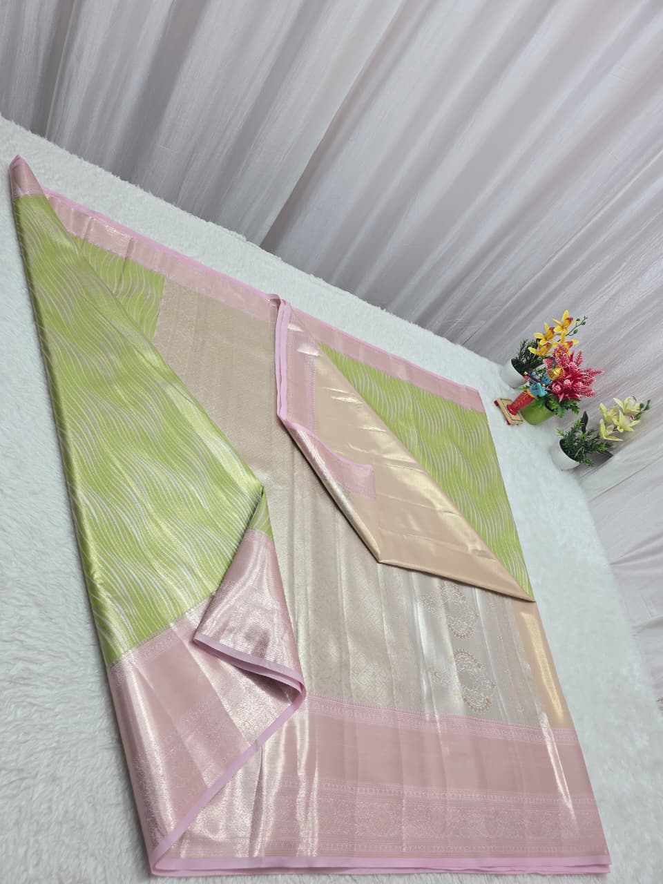 Green and pink fabric on a white surface with flowers in the background