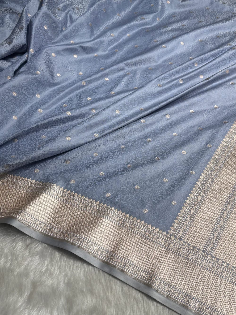 Blue fabric with gold patterns and border on a gray background