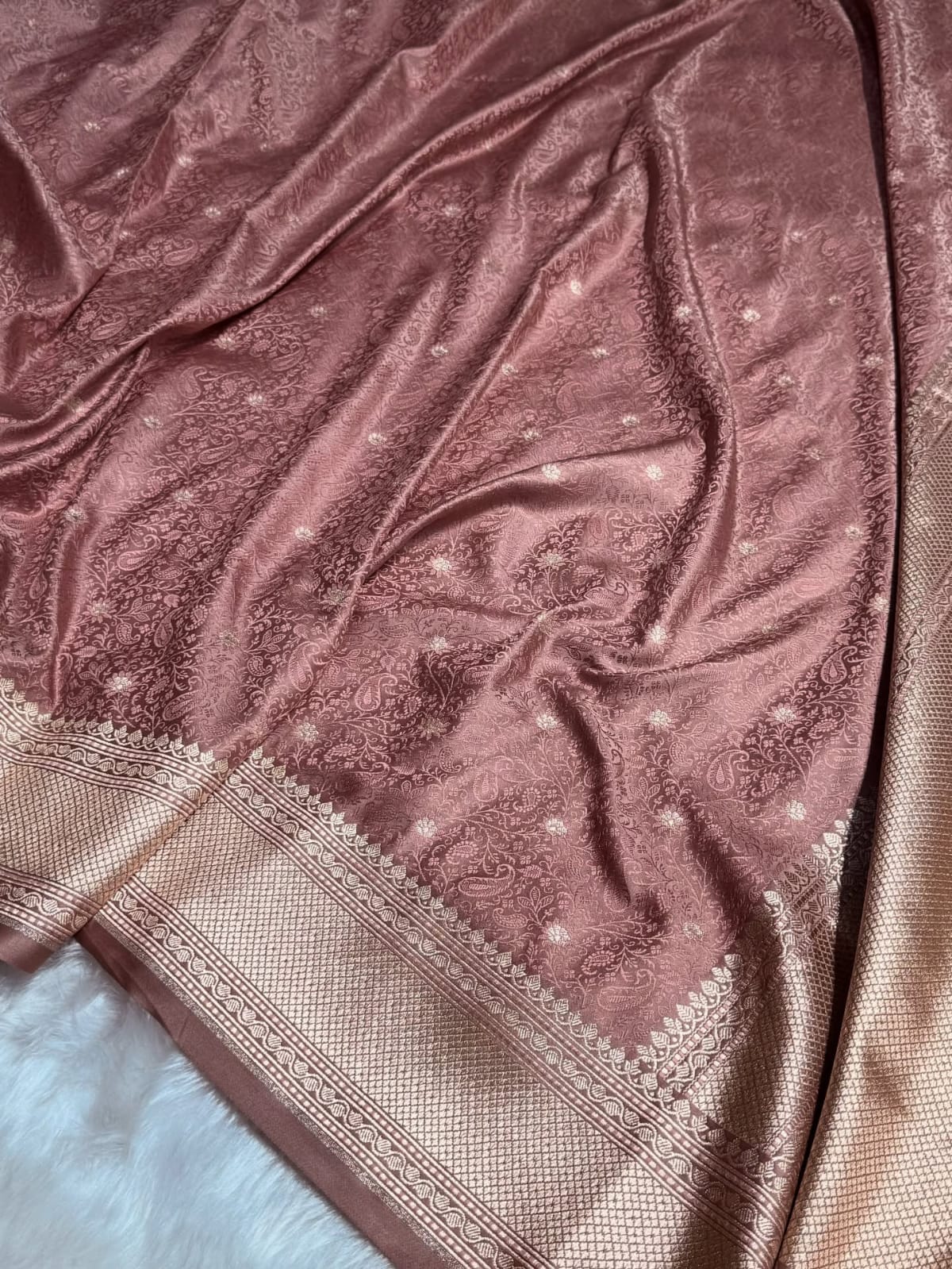 Pink saree with intricate patterns on a textured surface