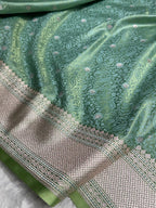 Green fabric with intricate patterns and a border on a white background