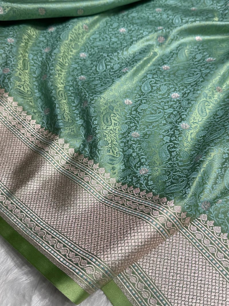 Green fabric with intricate patterns and a border on a white background