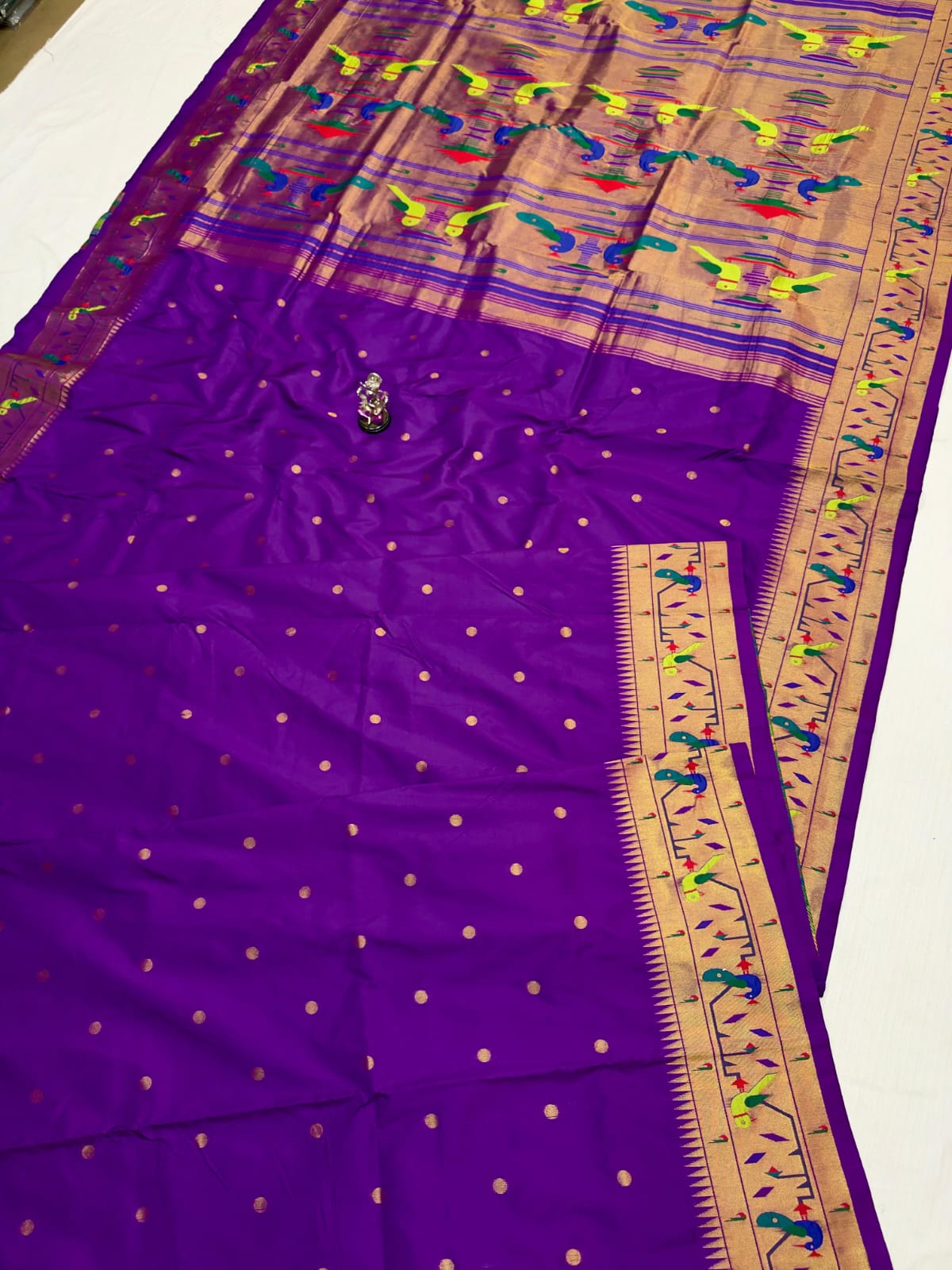Purple saree with a gold border and patterns on a white background